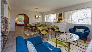 Un salon moderne comprenant un canapé, des fauteuils, une table à manger et un coin cuisine.