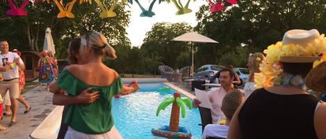 A poolside area with a swimming pool, lounge chairs, and a tiki bar.