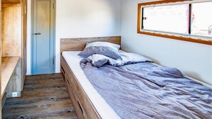 A single bed with a wooden headboard in a room with a wooden floor and a door. - Cozy ship in Hennigsdorf with house sea view (Hennigsdorf)