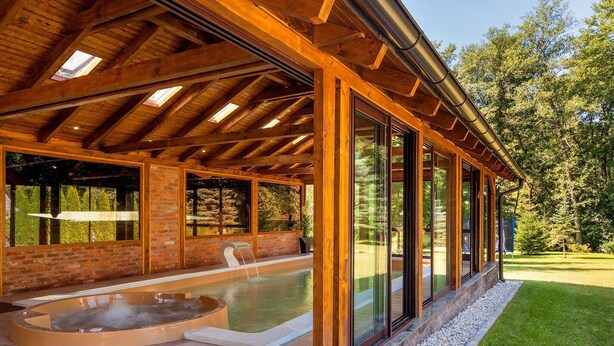 Une cabane en bois dotée d’un bain à remous, de grandes fenêtres et d’une terrasse.
