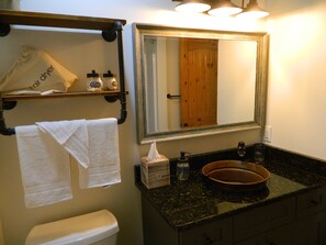 Ein Badezimmer mit Toilette, Waschbecken mit Spiegel und Handtüchern an einem Wäscheständer.