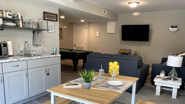 A modern living room with a pool table, a sofa, and a dining area with a table and benches. - Private Nashville Guest Suite - King Bed - Massage Chair - Private Entry (Hermitage)