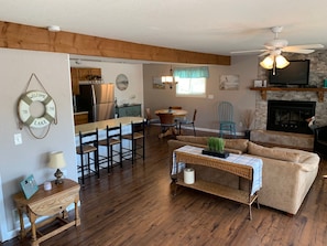 Cozy living space with a seating area, dining table, and kitchenette, featuring a fireplace and ceiling fan.