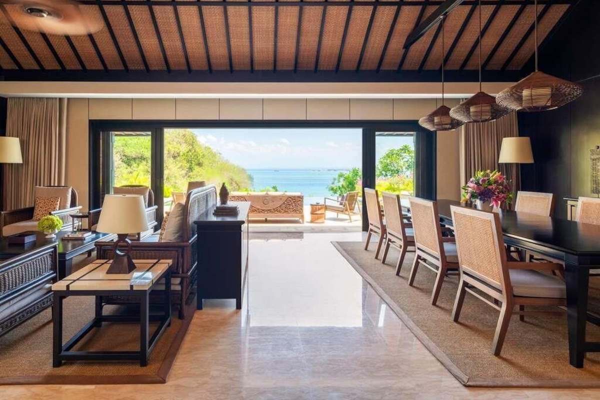 Amplia sala de estar con vista al mar, un comedor con sillas y una mesa, y un conjunto de sofás.