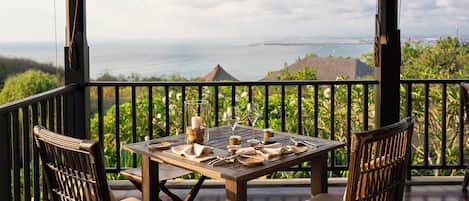 A wooden deck with a table set for two, overlooking a scenic landscape.