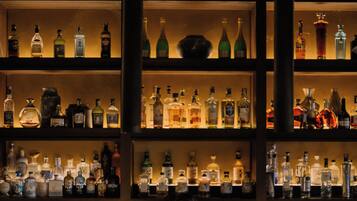 Eine Bar mit Regalen voller Spirituosenflaschen und einer Person, die einen Drink zubereitet.