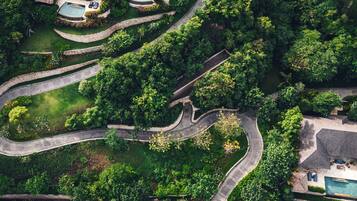 Vista aérea de un complejo turístico con múltiples piscinas, senderos sinuosos y abundante vegetación.