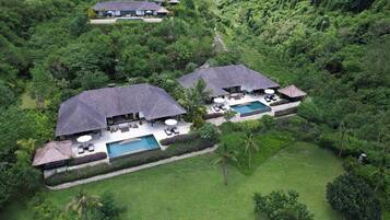 A large, two-story resort with a swimming pool, outdoor seating, and lush greenery.
