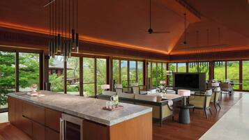 A spacious kitchen with a large island, modern pendant lighting, and a large TV.