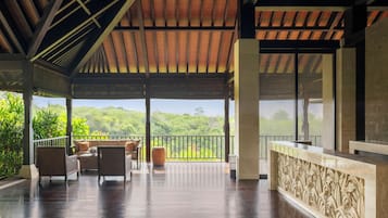 Un espacio al aire libre techado con suelo de madera, mobiliario y vista a zonas verdes.