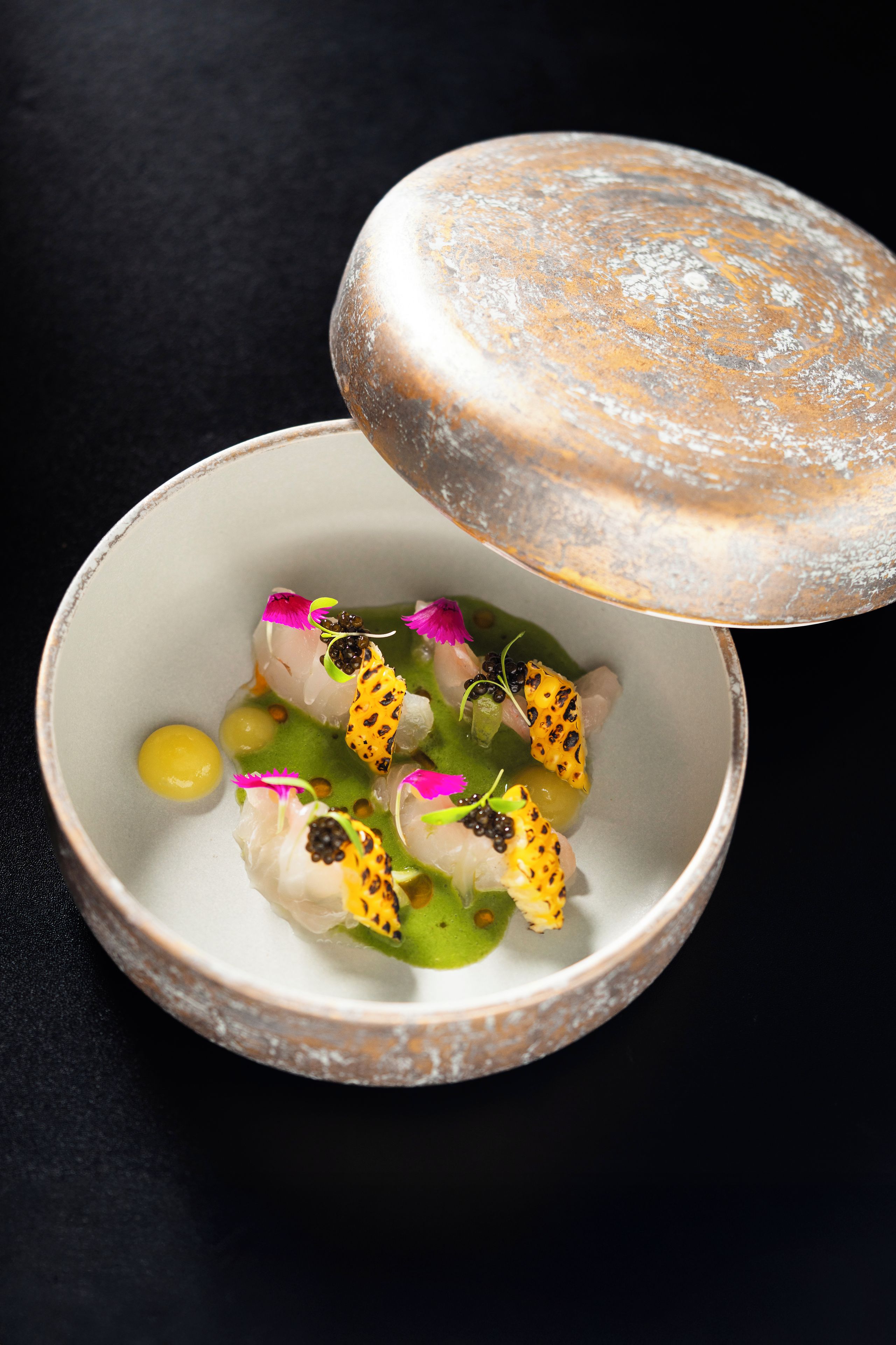 A bowl of food with a lid on a dark surface.