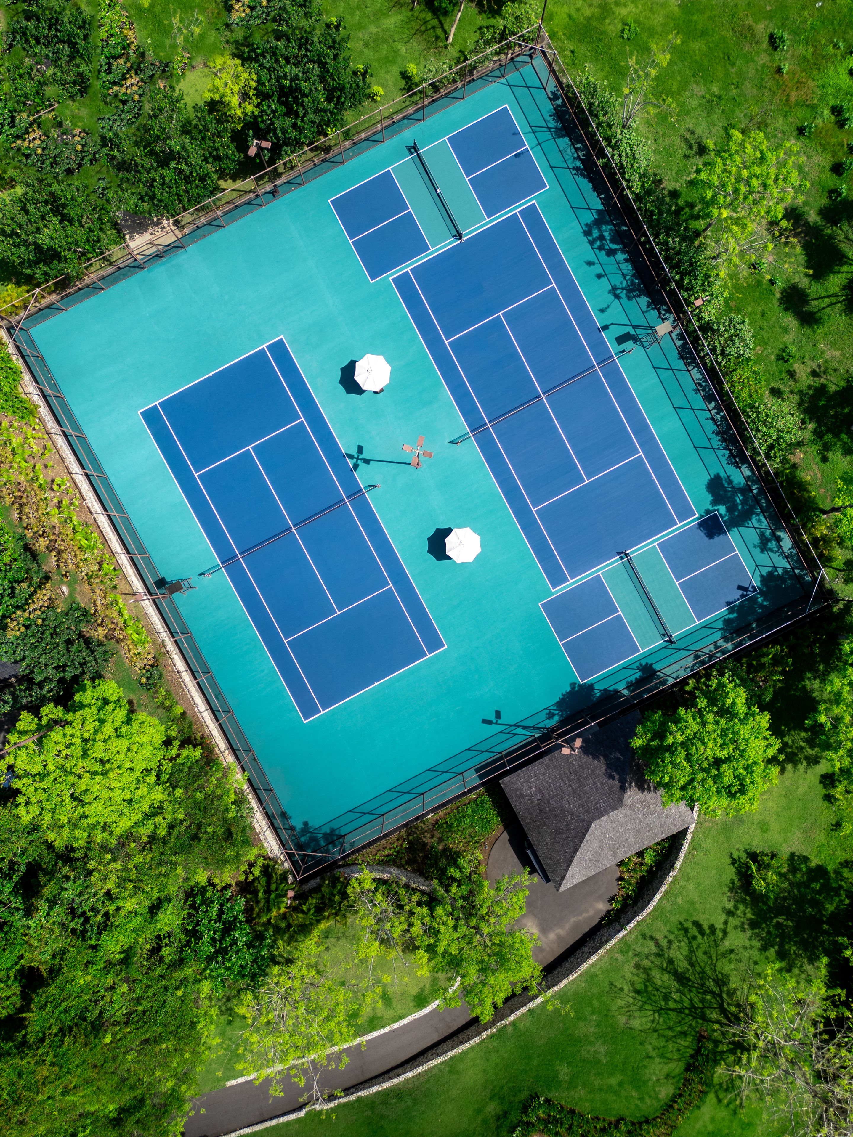 Vista aérea de una cancha de tenis rodeada de vegetación exuberante.