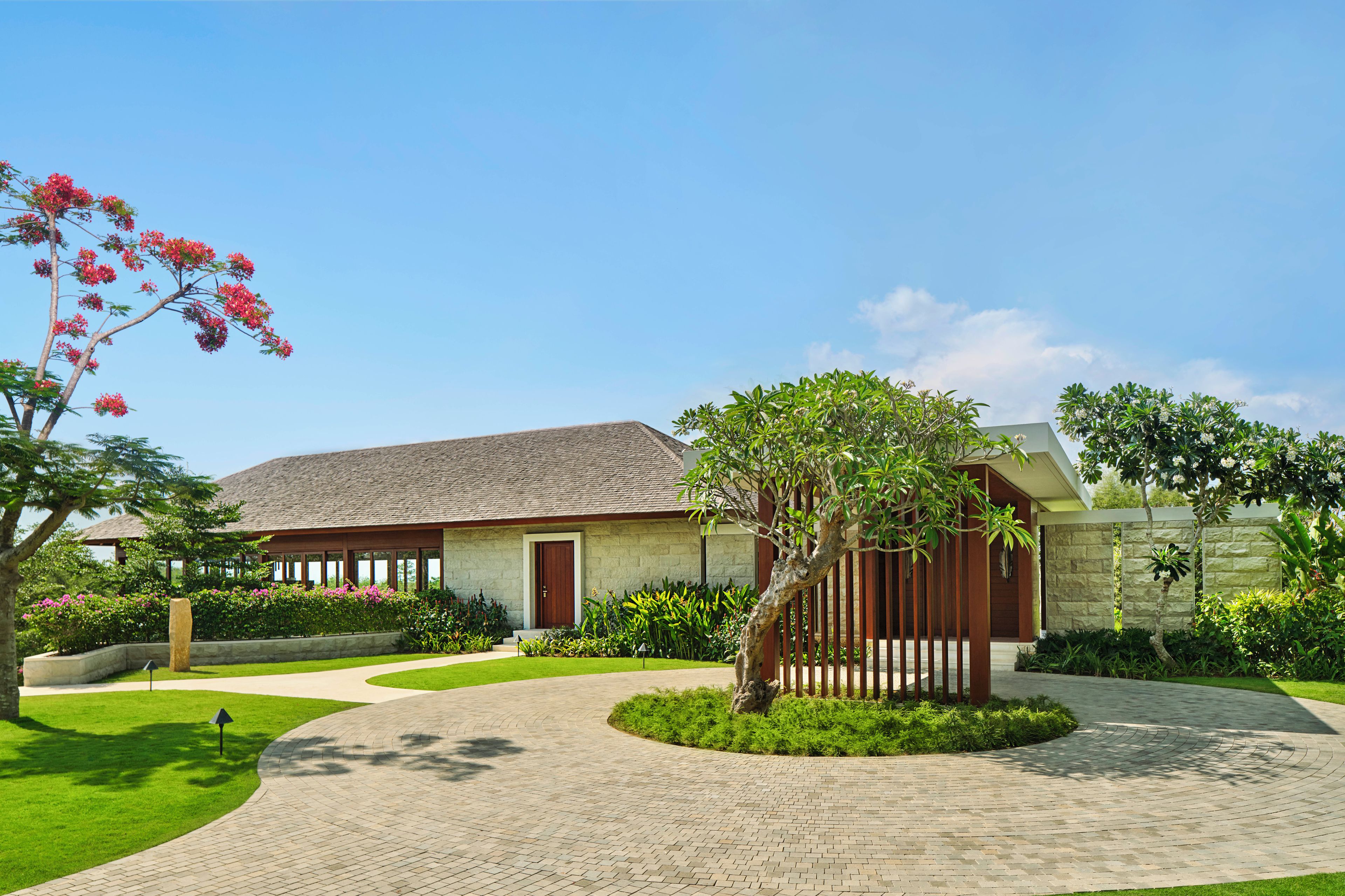 A residential property with a paved driveway, a well-maintained lawn, and a variety of flowering plants.