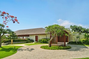 A residential property with a paved driveway, a well-maintained lawn, and a variety of flowering plants. - Raffles Bali (Jimbaran)