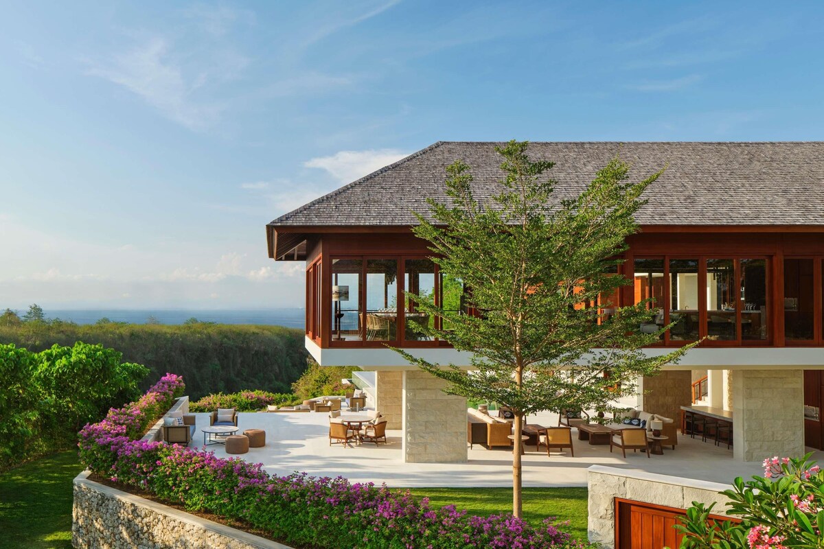 Uma casa moderna de dois andares com área de varanda, mobiliário externo e vista para a paisagem.