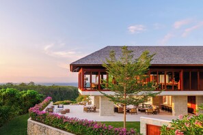 A modern house with a large patio area, outdoor furniture, and a view of the ocean. - Raffles Bali (Jimbaran)