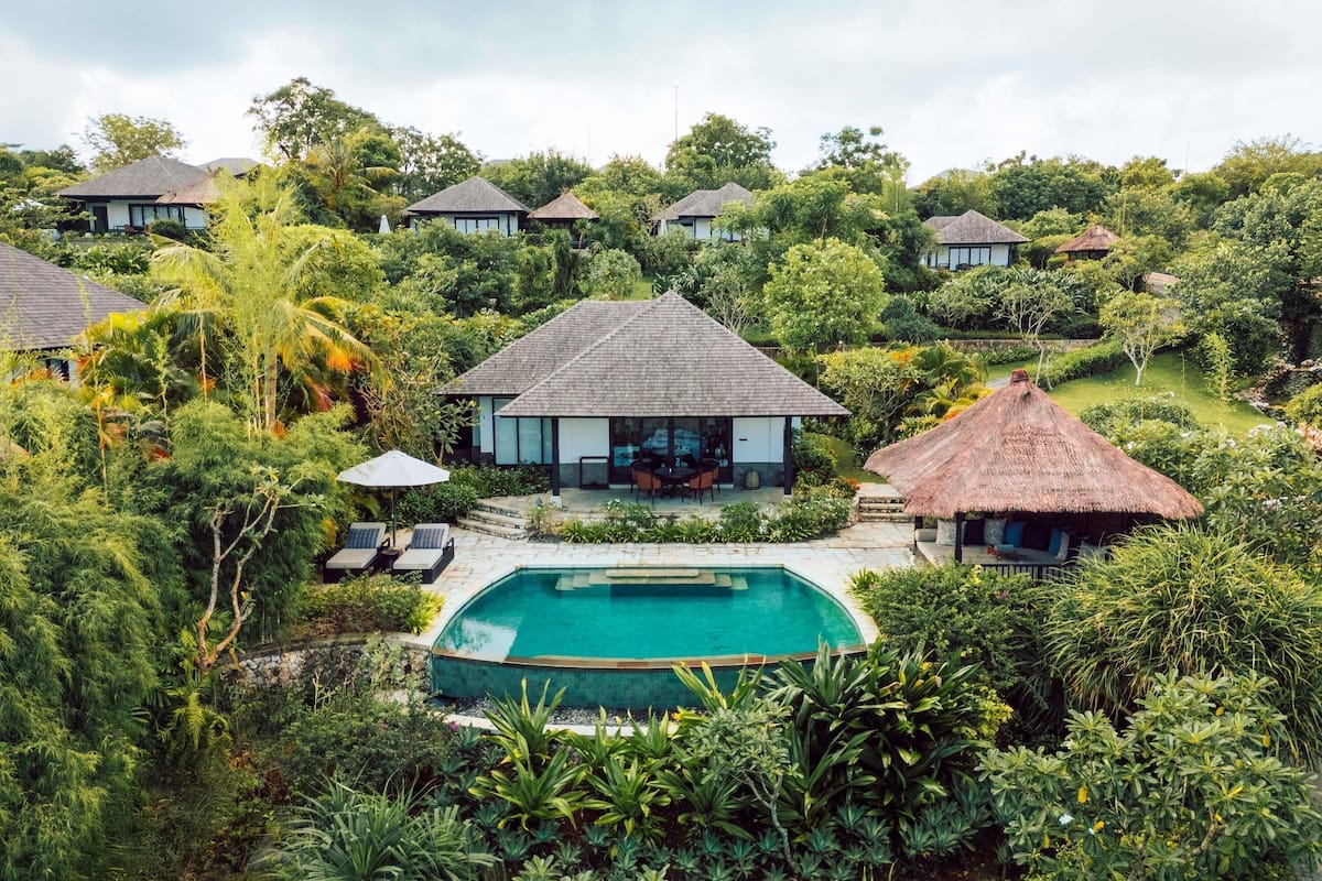 A resort with multiple thatched-roof cottages, a central pool, and lush greenery.