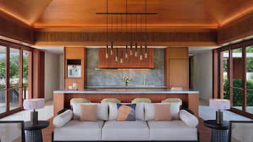 A modern living room with a sofa, a coffee table, and a dining area with a kitchen in the background.