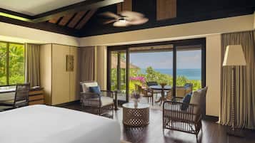 A hotel room with a bed, seating area, and a view of the ocean.