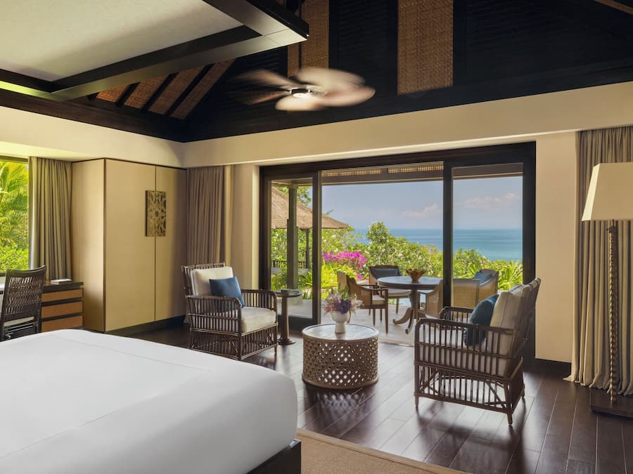Une chambre d’hôtel avec un lit, un coin salon et une vue sur l’océan.