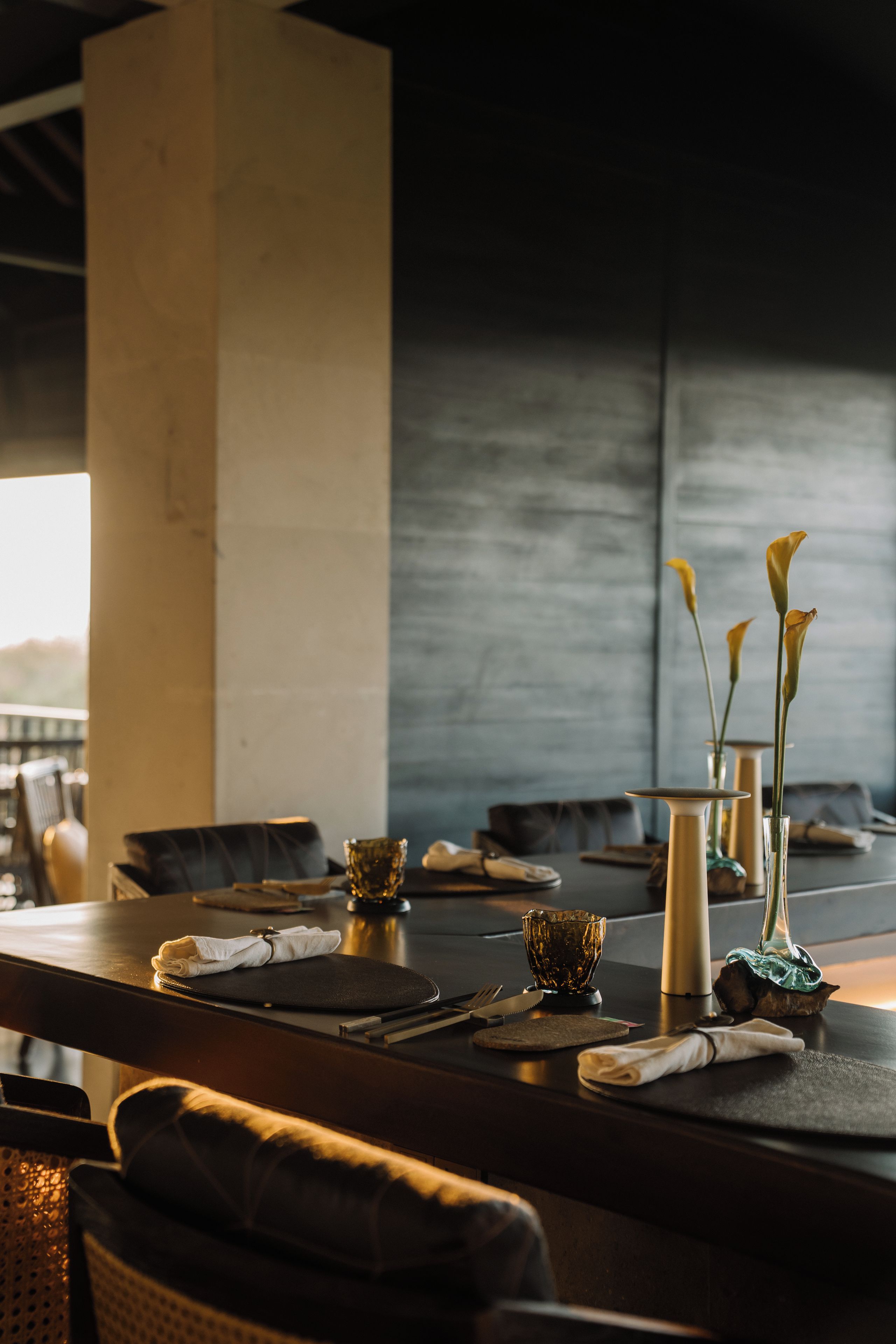 A dining table set with cutlery, a glass bowl, and a vase with flowers.