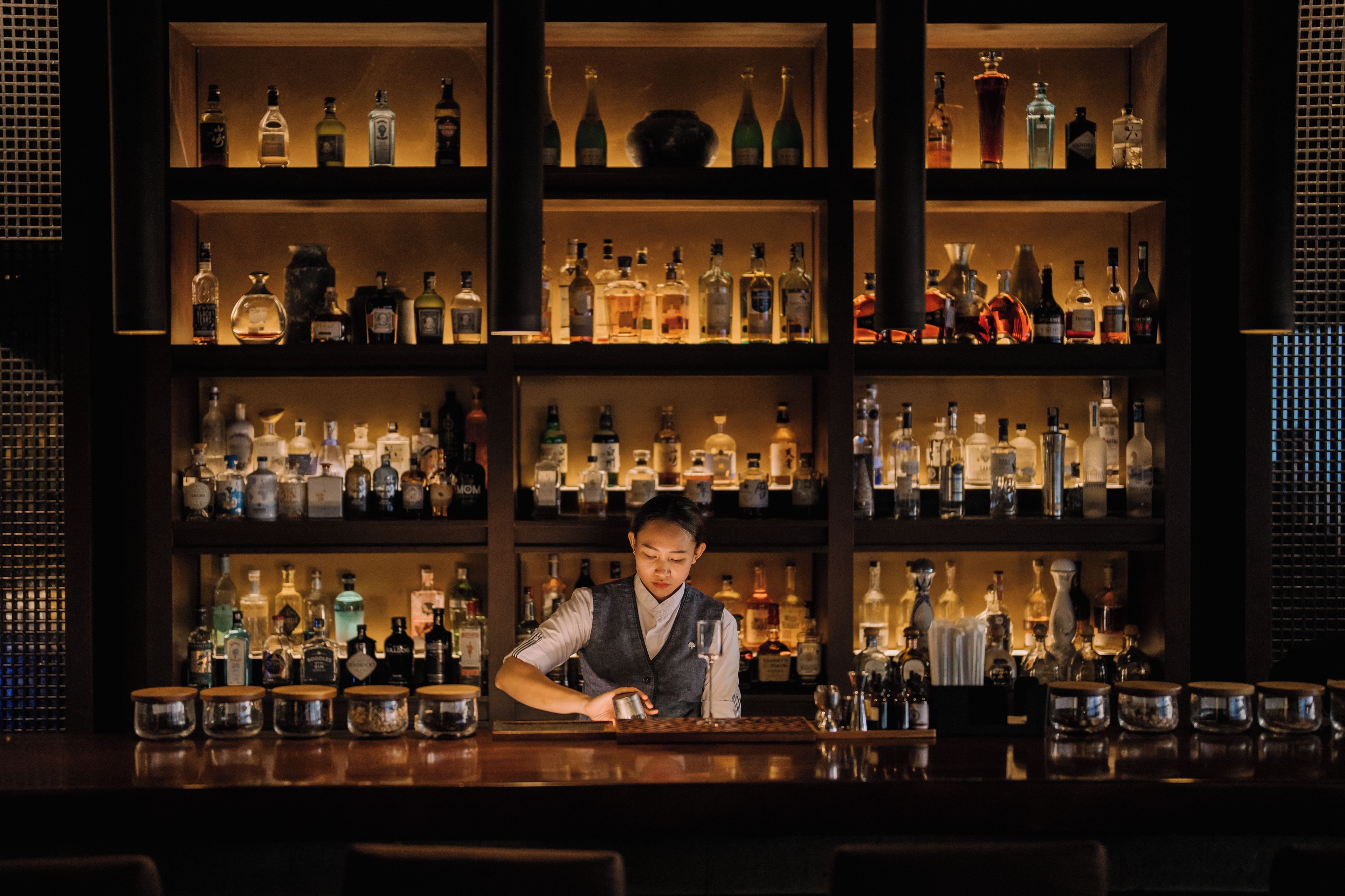 Un bar con estantes llenos de botellas de licores y vasos.