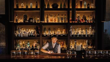 Un bar con estantes llenos de botellas de licores y vasos.