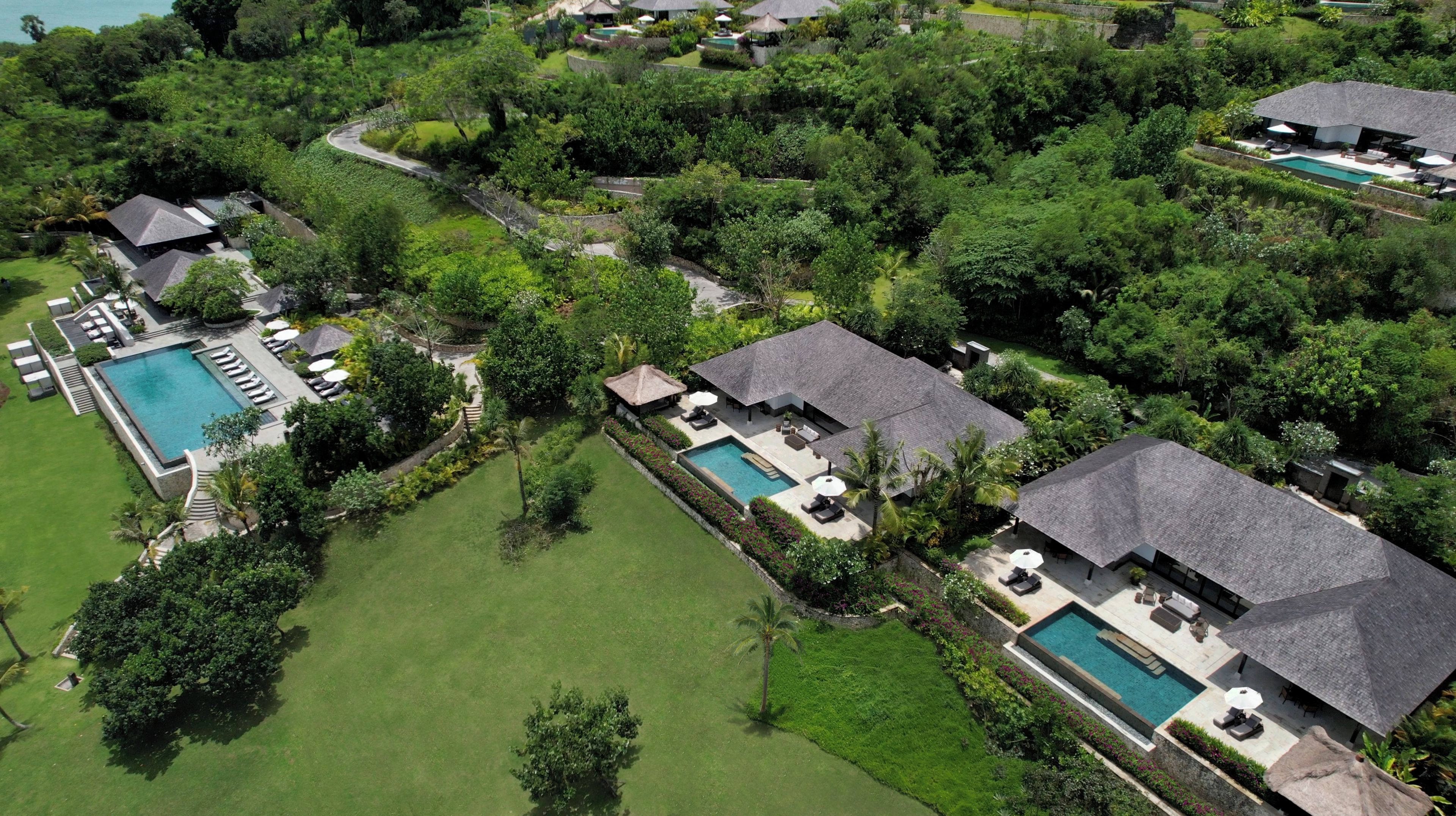 Vista aérea de un resort con múltiples piscinas, exuberante vegetación y diversas zonas de estar al aire libre.