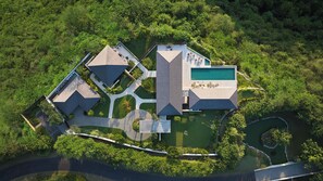Een luchtbeeld van een modern resort met meerdere gebouwen, een zwembad en aangelegde tuinen.
