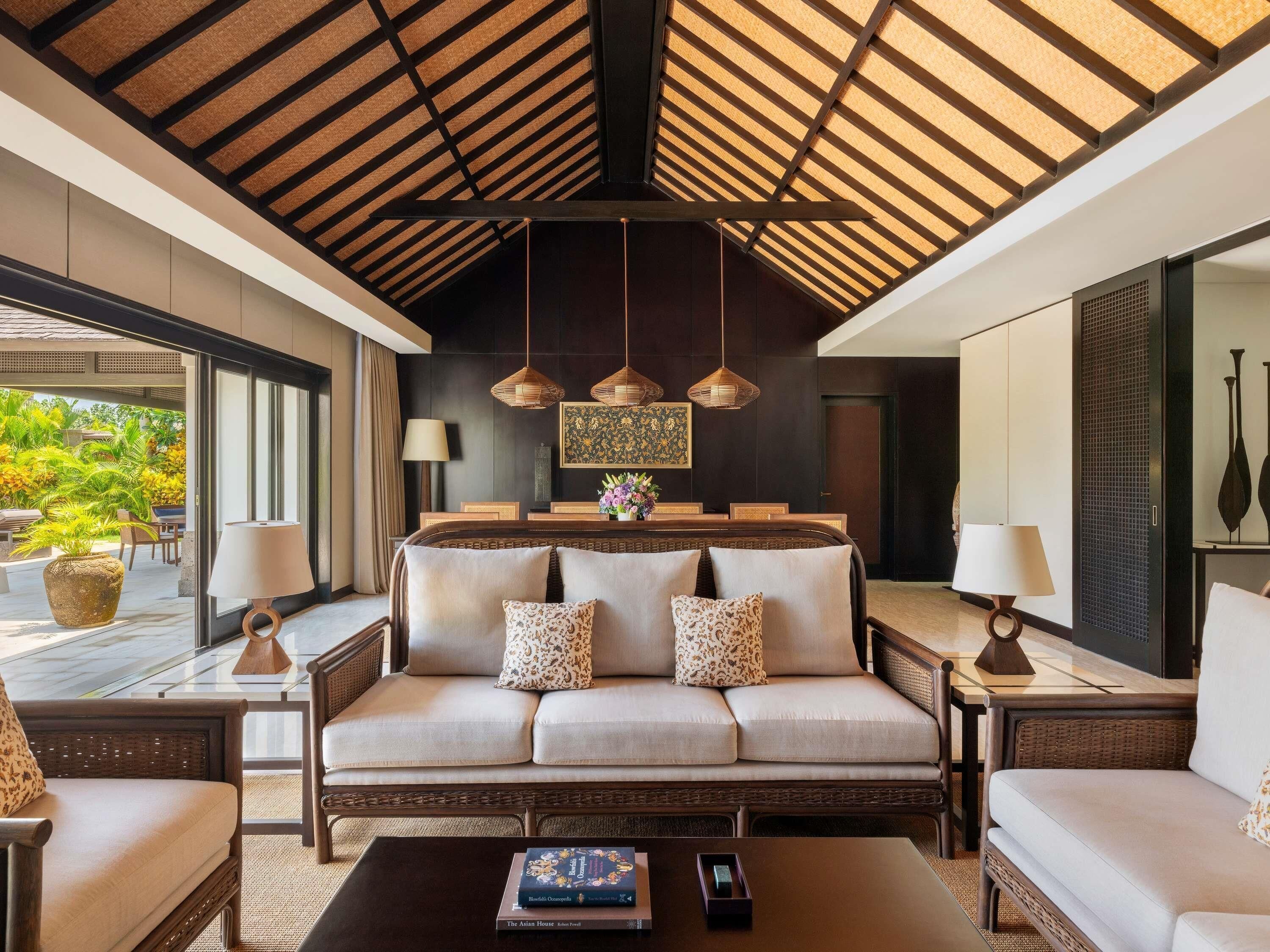 A modern living room with a sofa, two side tables, a coffee table, and a dining area with a table and chairs.