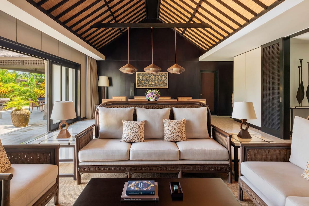 A modern living room with a sofa, two side tables, a coffee table, and a dining area with a table and chairs.