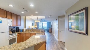 A modern kitchen with granite countertops, wooden cabinets, and a built-in oven. - Myrtle Beach | Family Beach Retreat | Pool + Beach | 2BR (Myrtle Beach)