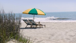 Une plage avec deux chaises longues et un parasol.