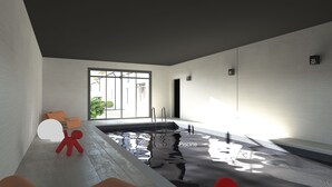 Piscina interior moderna com paredes de vidro transparente, uma escultura abstrata vermelha e uma janela grande que permite entrada de luz natural.