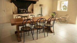 Uma sala de jantar com mesa de madeira e cadeiras de metal, lareira e janela com vista.