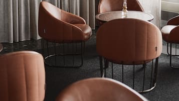 A hotel room with a large window, a round table, and four brown leather chairs.