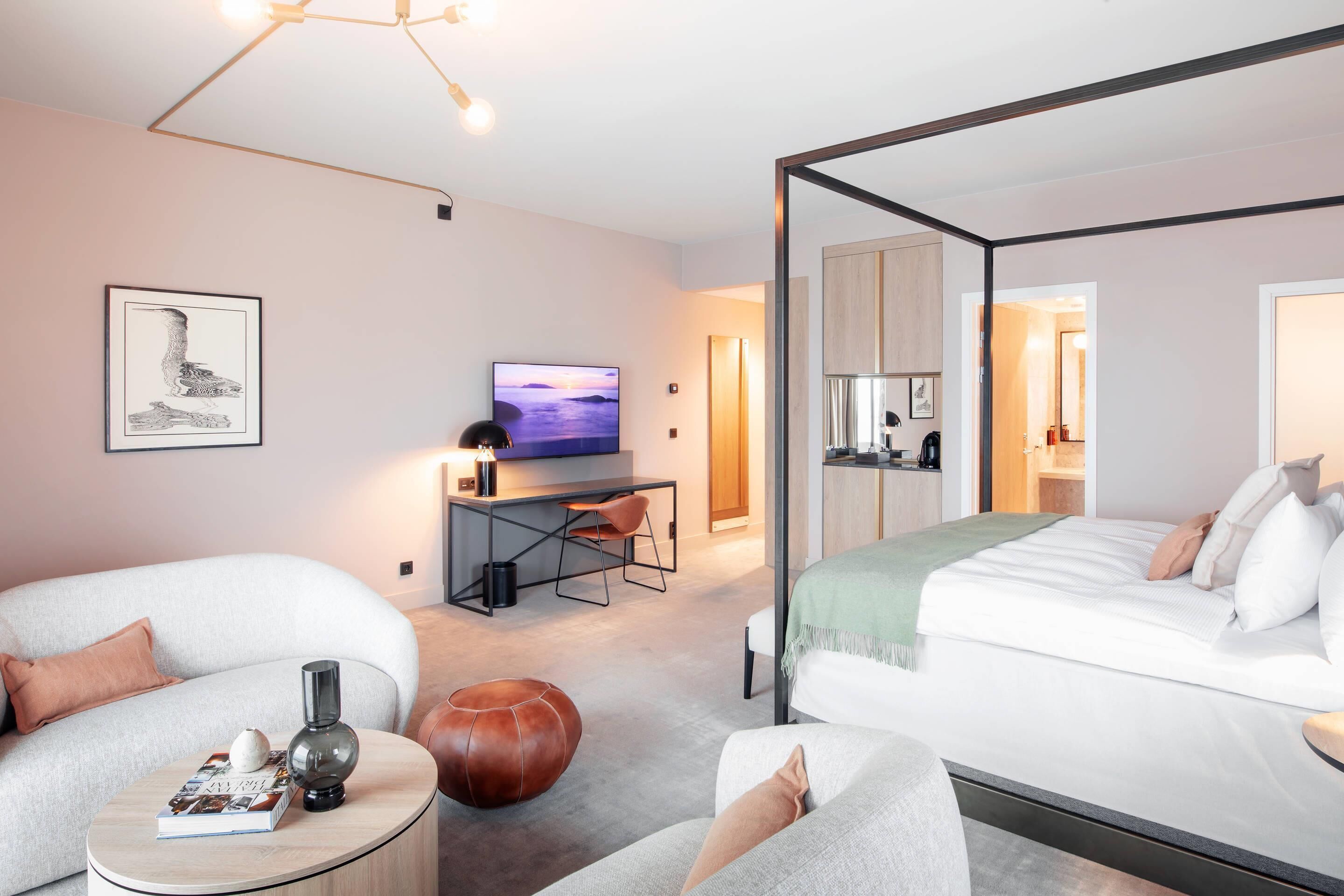 Een moderne hotelkamer met een bed, een bureau met televisie, een bank en een salontafel.