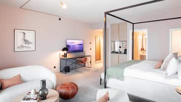 Een moderne hotelkamer met een bed, een bureau met televisie, een bank en een salontafel.