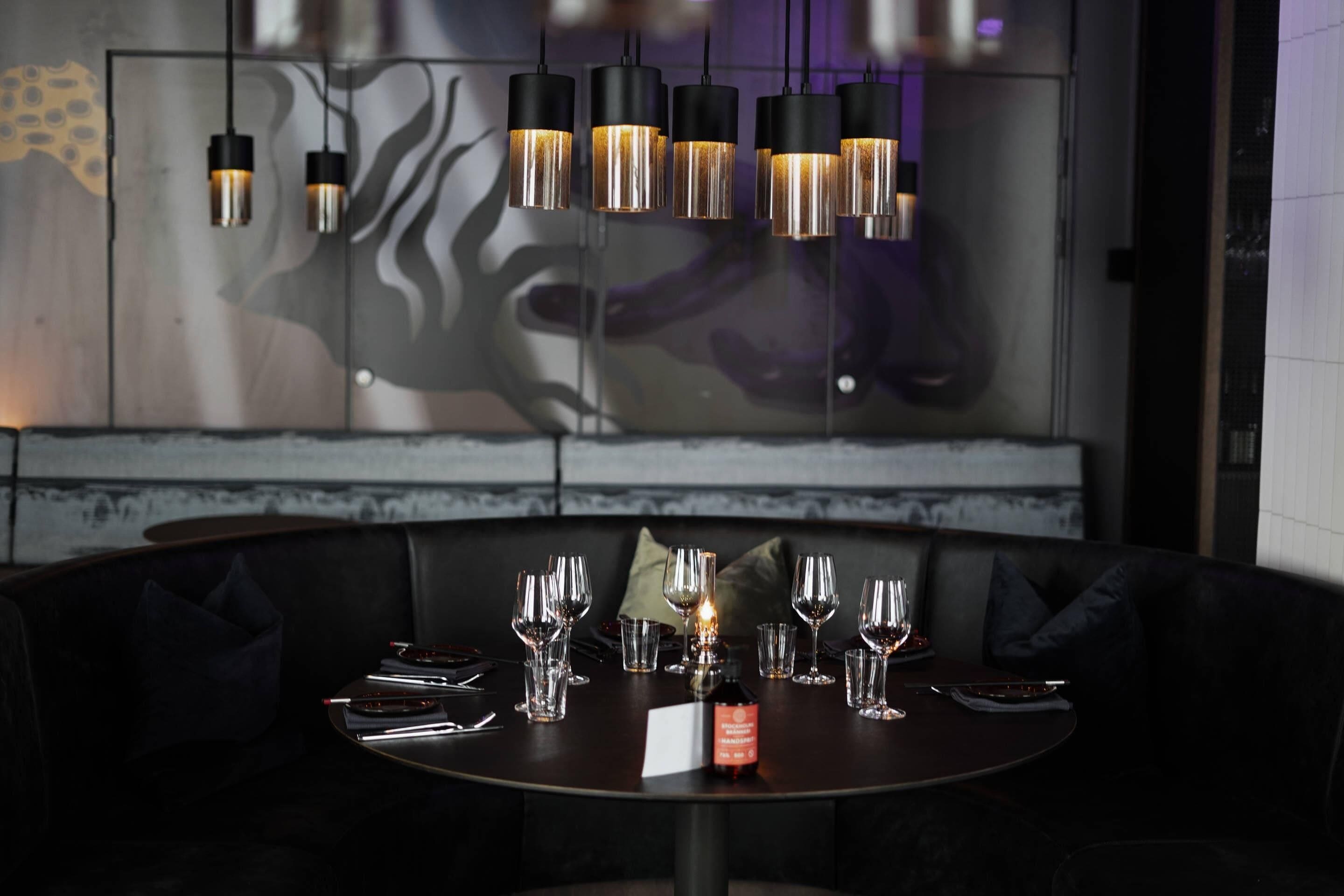 A dining area with a round table set for a meal, a bottle of wine, and a menu.