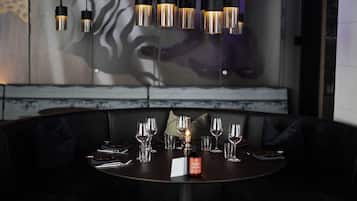 A dining area with a round table set for a meal, a bottle of wine, and a menu.
