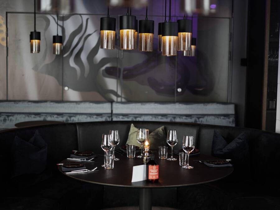 A dining area with a round table set for a meal, a bottle of wine, and a menu.