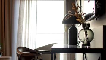A modern living room with a minimalist design, featuring a black table, a leather chair, and a vase with dried plants.