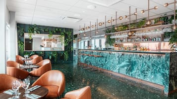A bar area with a marble countertop, bar stools, and a variety of bottles.