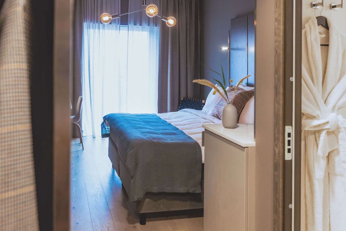 Une chambre moderne avec un lit, une table de chevet et une grande fenêtre avec des rideaux.