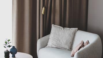 A modern living room with a grey sofa, a round wooden coffee table, a brown leather ottoman, and a potted plant.
