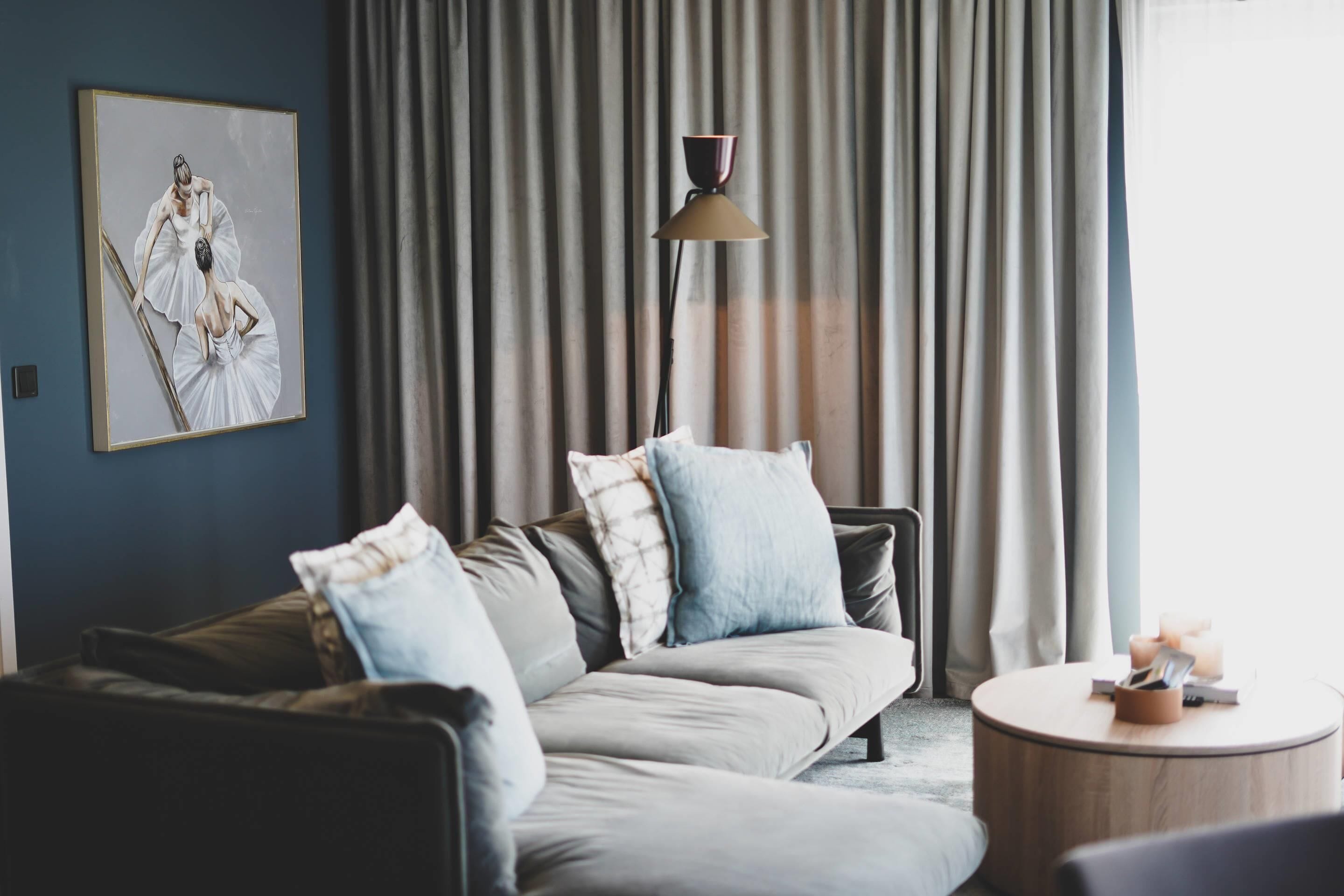 En moderne stue med sofa, puder, lampe og et billede på væggen.