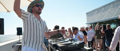 A DJ performing on a stage with a crowd of people.