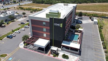 A hotel with a rooftop pool, a parking lot, and a sign indicating it's a Hilton Suites hotel.