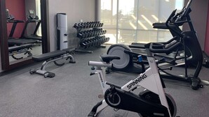A gym with a spinning bike, treadmills, and dumbbells.