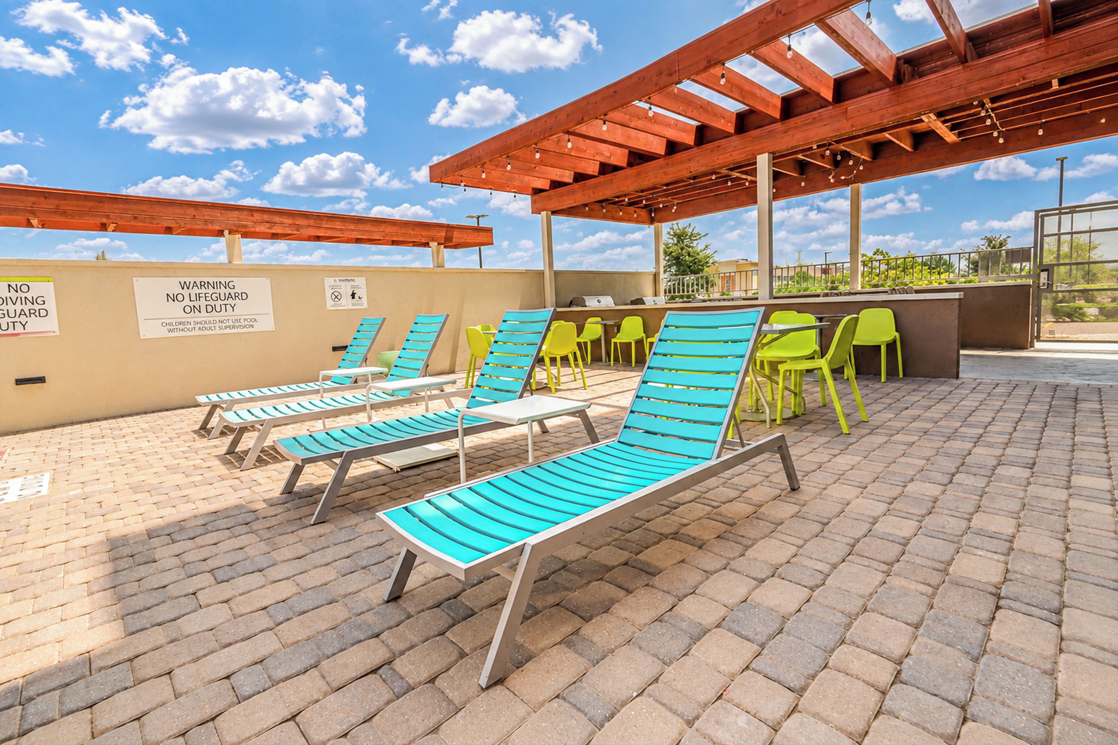 An outdoor pool area with lounge chairs and a barbecue setup.
